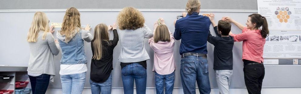 Lehrende und Lernende arbeiten gemeinsam an einer Pinnwand (Foto: Universität Passau)