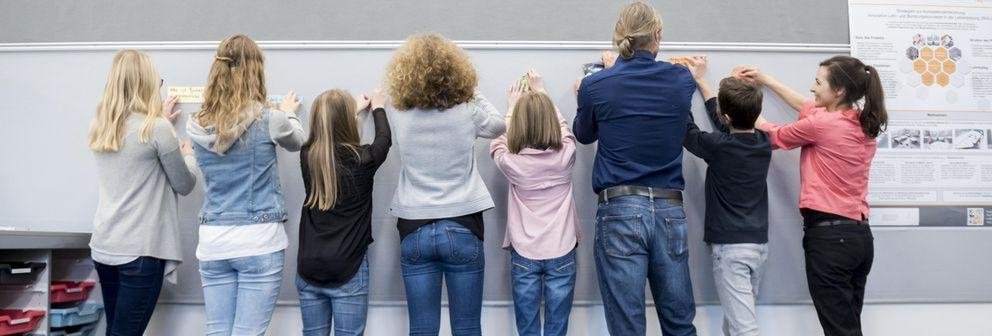 Lehrende und Lernende arbeiten gemeinsam an einer Pinnwand (Foto: Universität Passau)